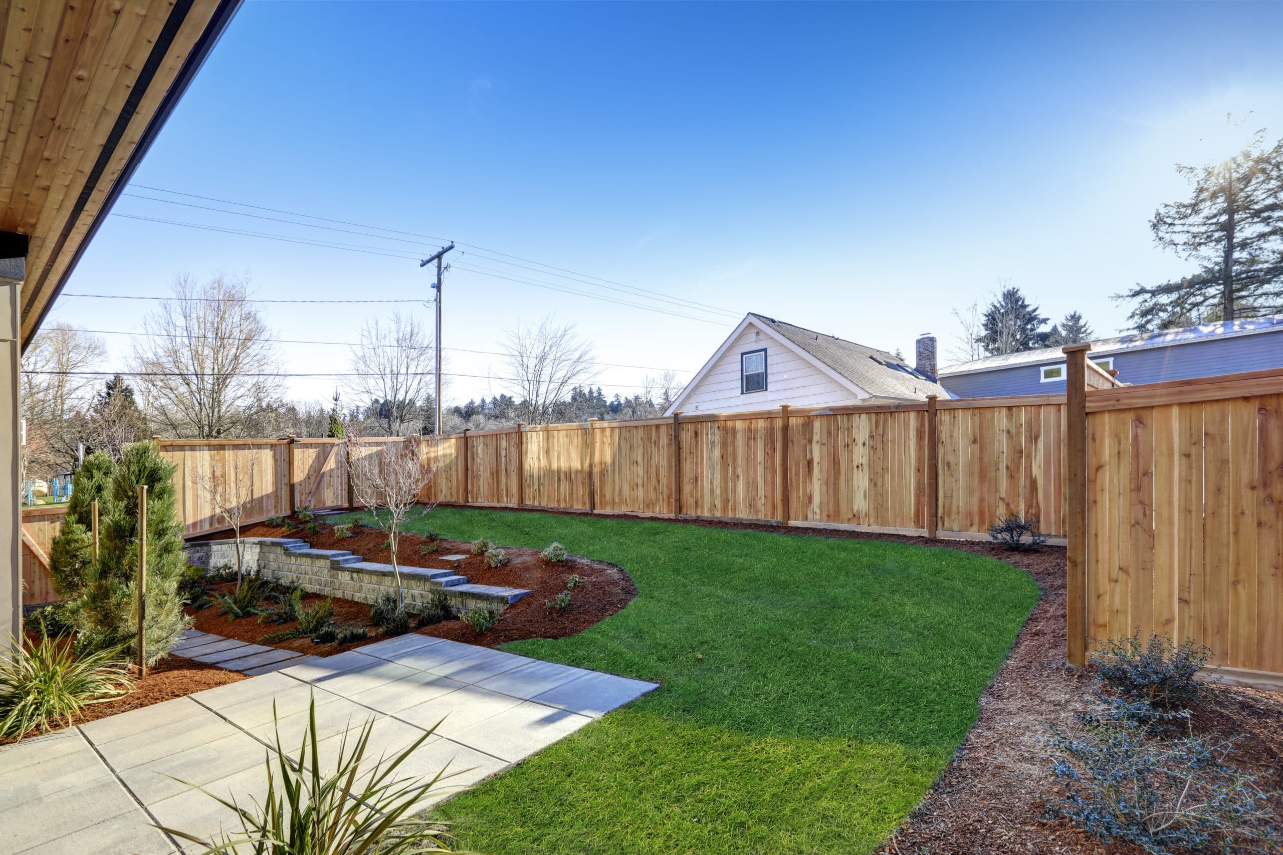 Sloped backyard surrounded by wooden fence Luxury New construction home with open floor plan Fencing