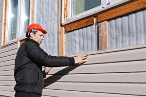 man installing siding on house